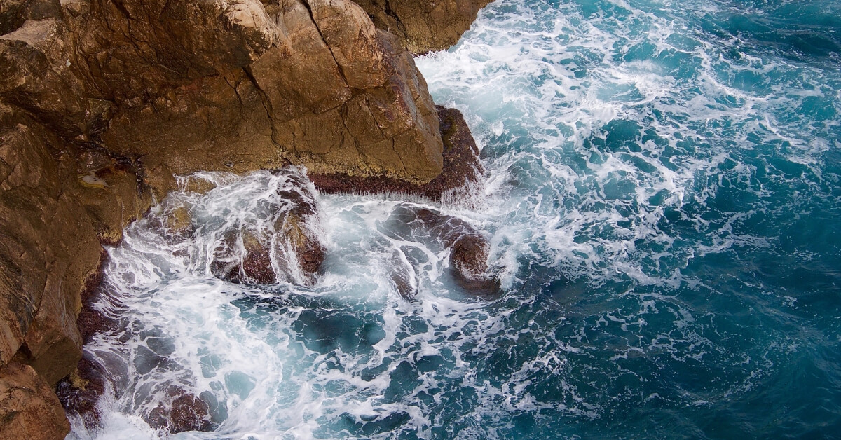 waves crashing into a rock cliff