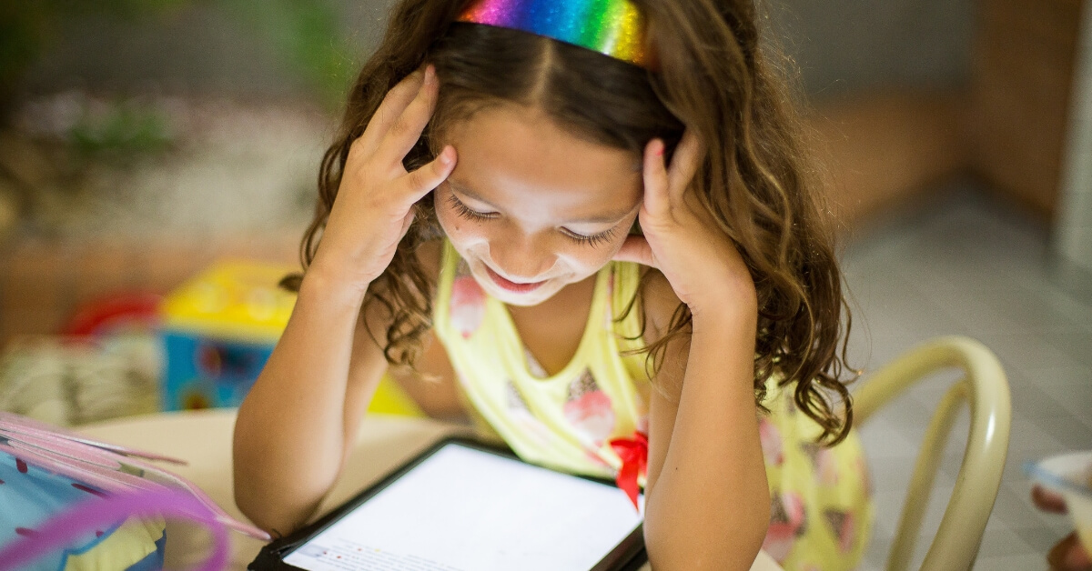young girl smiling down at an iPad