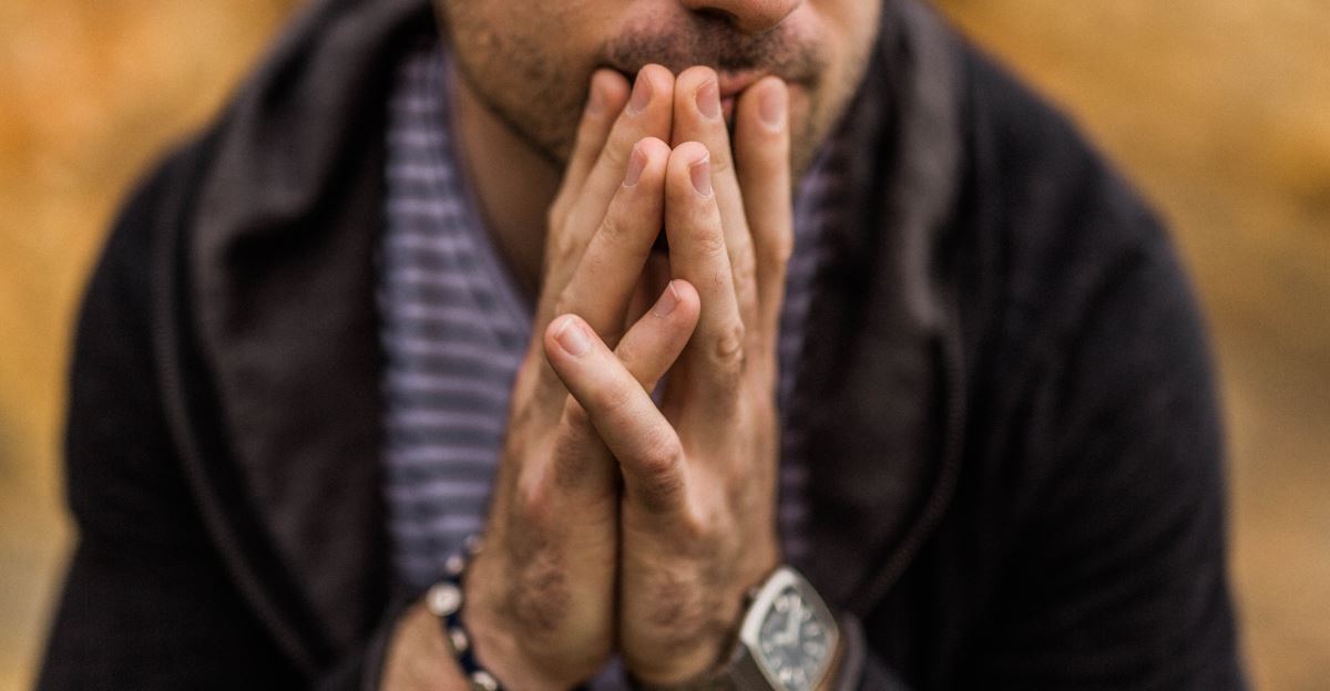 Man with hands together in front of his face looking thoughtful