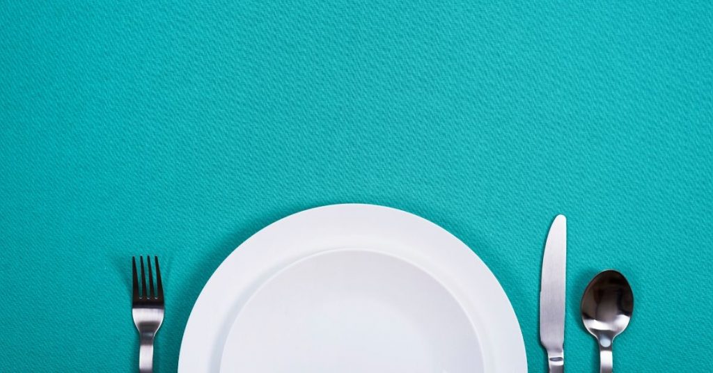 plate and cutlery on teal background